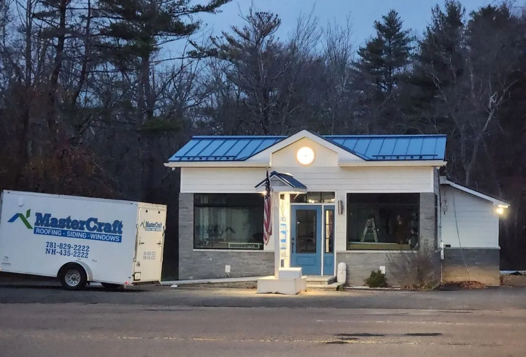 MasterCraft's Hingham office at night, with a blue metal roof and a MasterCraft work trailer