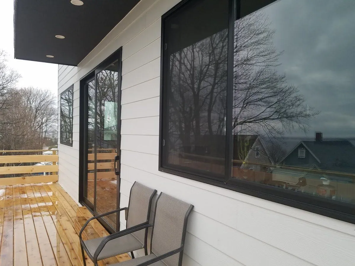 Black replacement windows and a sliding door set in white Hardie plank siding in Quincy, MA